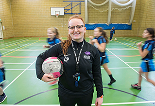 A student holding a football in a gymnasium