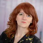 A woman with red hair looks at the camera 