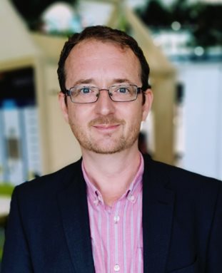 James Kendrick in the Checkland building foyer wearing a bright pink shirt