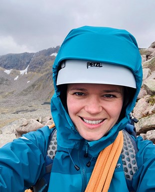 Lorna Linch looking at the camera in outdoor gear in the mountains