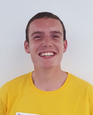 A smiling James Lewington in a bright yellow t-shirt