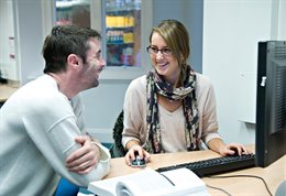Lecturer testing a students English at a computer