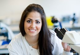 Student smiling with microscope