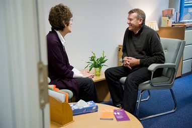 Two people in chairs facing each other and talking