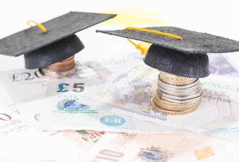 International banknotes with university 'mortarboard' hats on piles of coins