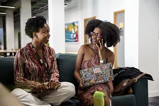 Students talking on a sofa, with laptops