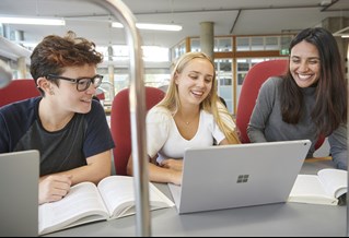 Three students working on laptops in the library 