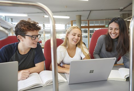 Three students on laptops in the library
